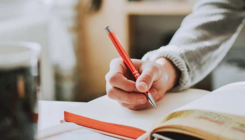 Writing a faith story and reflecting on Christian faith with pen and notebook.