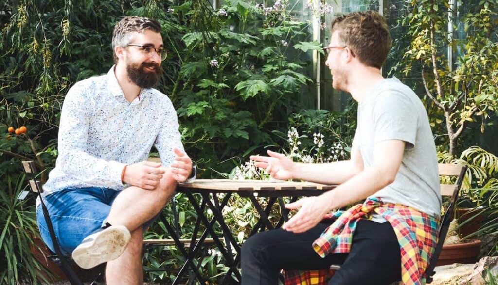 Two men having a faith conversation outdoors, explaining the Gospel and sharing Christian faith.