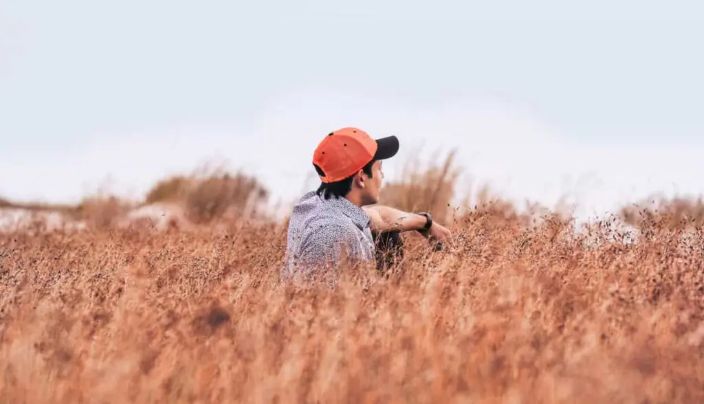 Man thoughtfully sitting in field illustrating intentional gratitude and faith journey