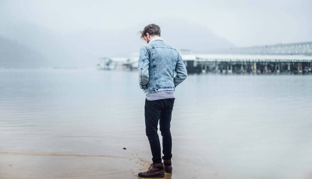 Man looking out over water reflecting on hurting and God's love.