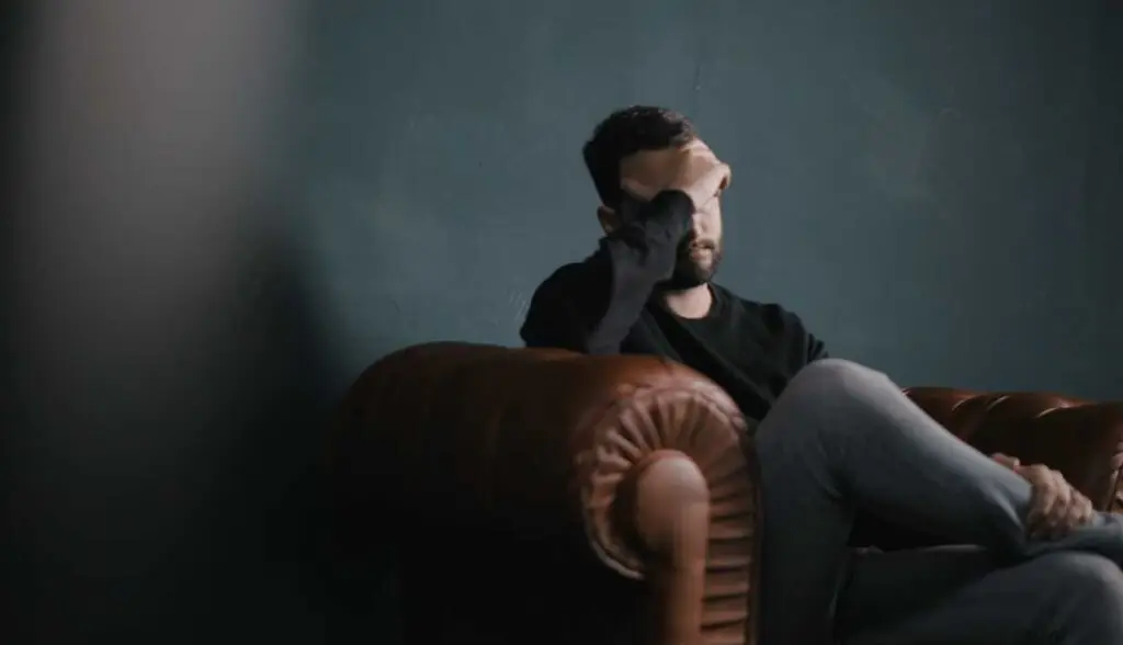Man covering face with hand expressing anxiety and worry, Christian faith and discipleship.