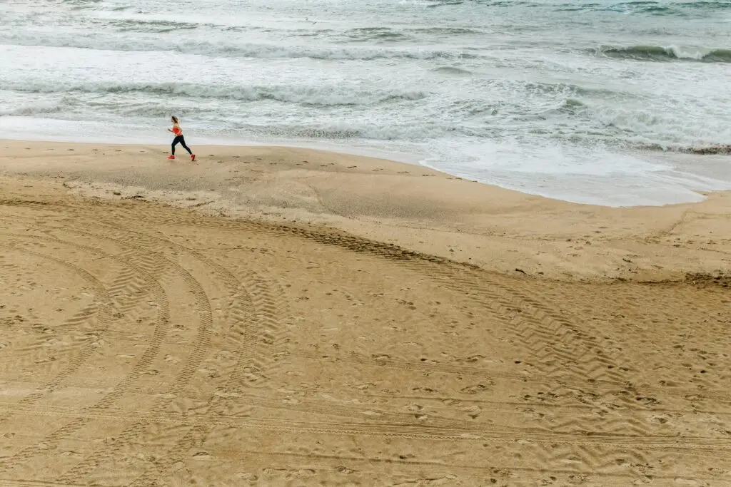Woman running on beach illustrating self-control and holistic wellness.