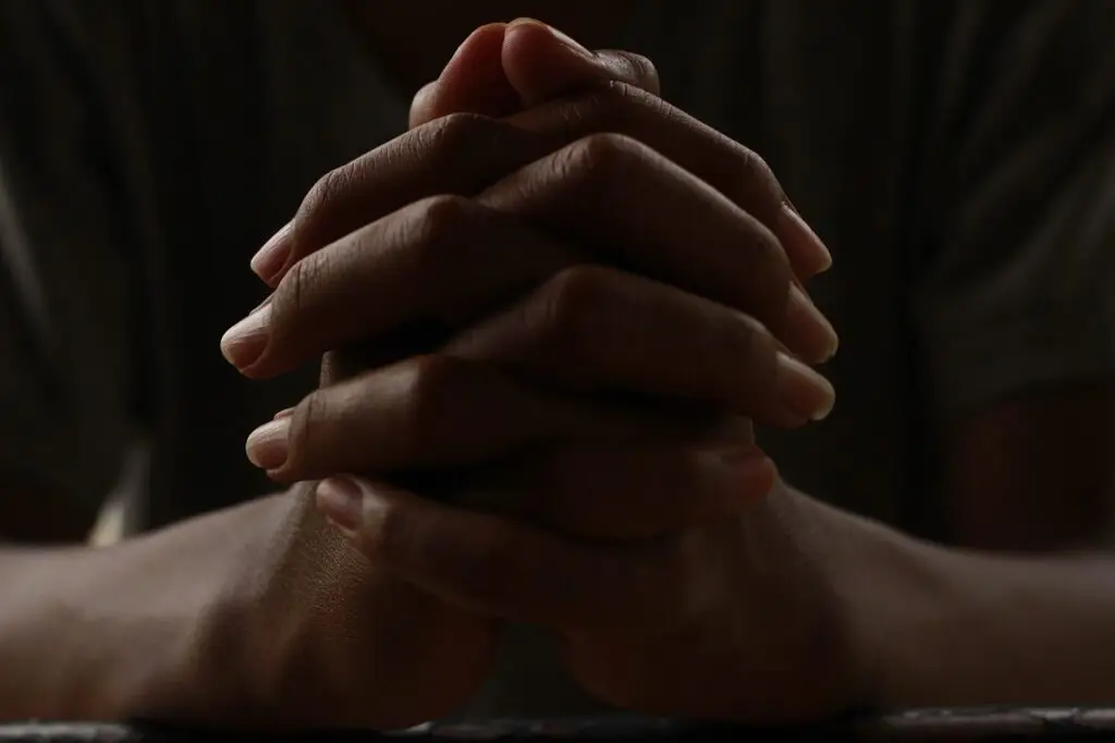 Praying hands symbolizing forgiveness and Christian faith.