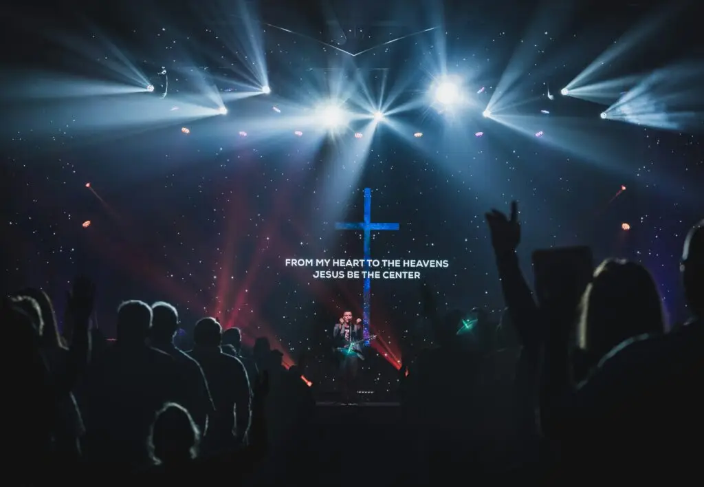 Christian worship service with cross and stage lighting, celebrating faith and Jesus.