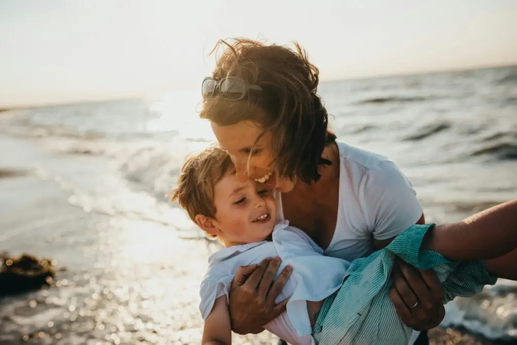 Mother and child embracing at the beach, symbolizing healthy family relationships and joy.