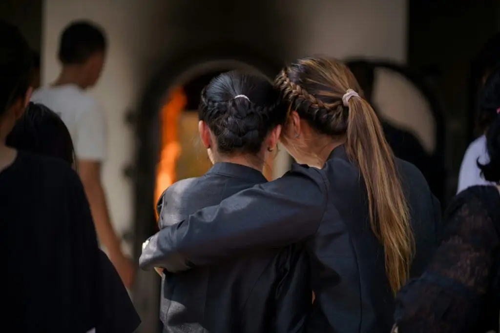 Woman embracing another in mourning, Christian support and comfort after loss.