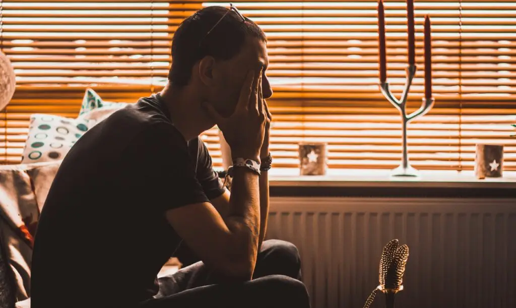 Man with hands covering face, illustrating spiritual warfare and negative thoughts.
