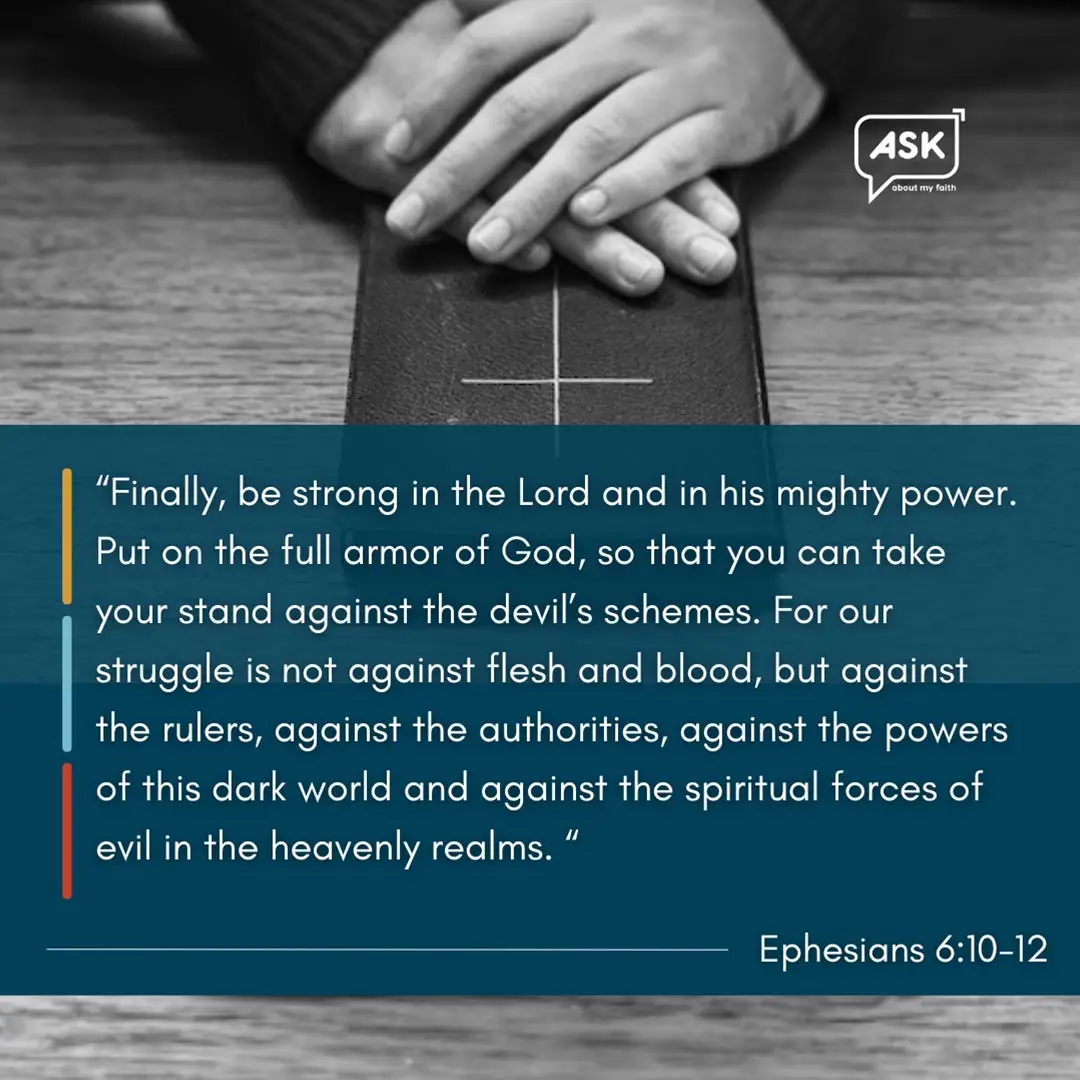 Praying hands clasped over Bible, Ephesians 6:10-12 scripture, spiritual armor illustration.