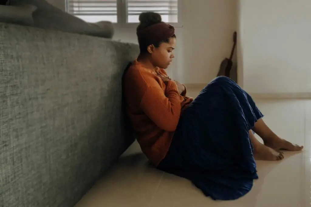 A woman sits on a floor anxiously